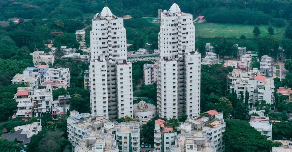 A drone captures a scenic cityscape featuring high-rise buildings surrounded by lush greenery.
